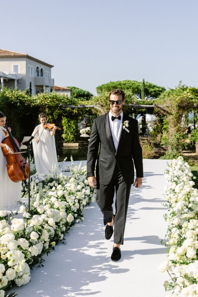 Groom walking down the aisle at Airelles Saint-Tropez during luxury outdoor wedding ceremony.