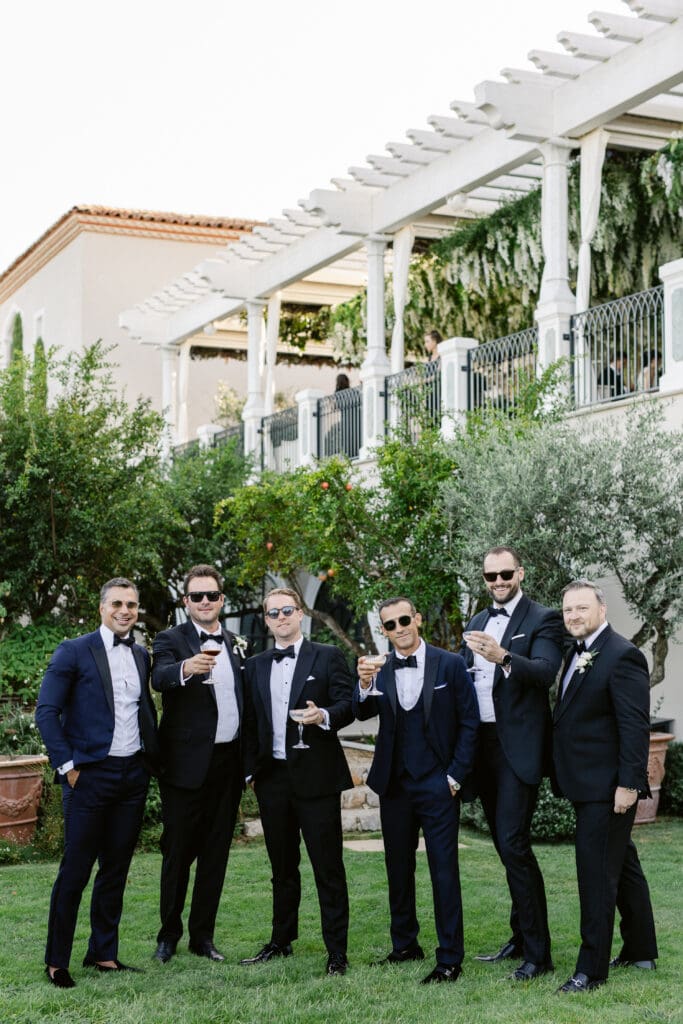 Groomsmen in black tie toasting during stylish cocktail hour at French Riviera wedding.