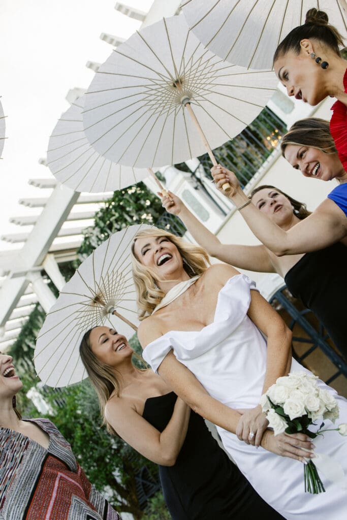 Joyful bride under parasols captured candidly at destination wedding in South of France.