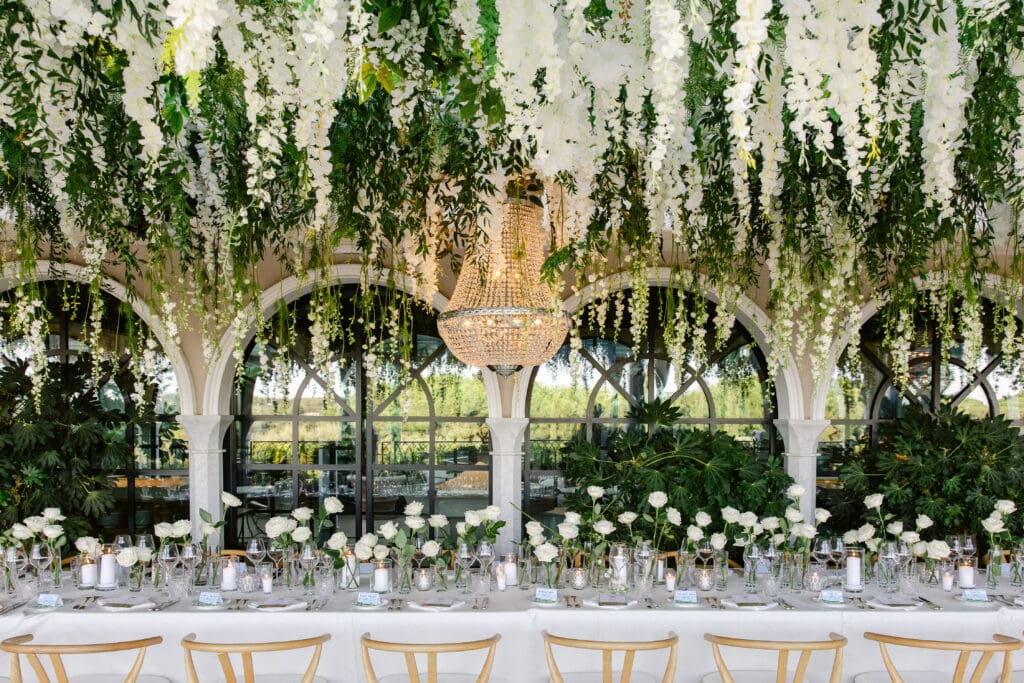 Luxury wedding reception setup at Airelles with elegant white roses and chandeliers.