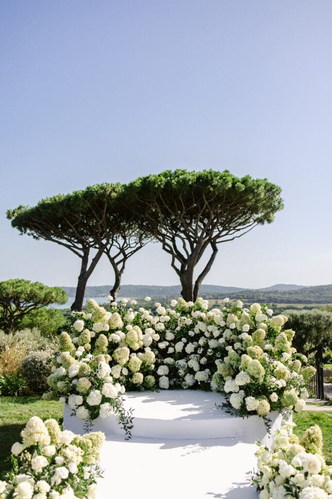 White floral wedding arch at Airelles La Messardière, luxury destination wedding in South of France.