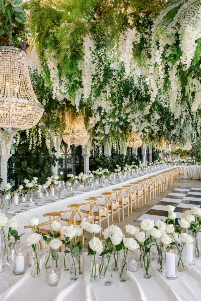 Long floral-decorated wedding table with chandeliers at Airelles Saint-Tropez reception.